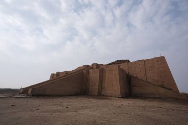 Bulutlu gökyüzünün altında büyük basamakları ve tuğla duvarları olan antik ziggurat yapısı
