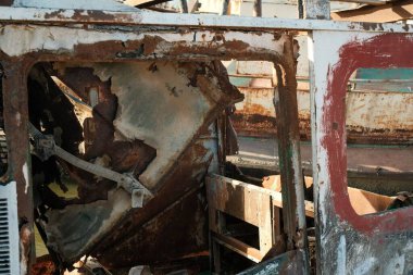 Terk edilmiş ve paslanmış bir tekne, soyulmuş boyalar ve aşınmış metal yüzeyler, çürüme ve ihmal hissi uyandırıyor.