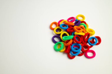 Beyaz arka plana dağılmış renkli saç bağları.