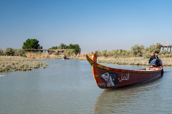 Насирия, Ирак - 20 ноября 2025 года: Группа туристов на традиционных лодках Машуф приближается к памятнику Аль-Шахиду в Чибаишских болотах