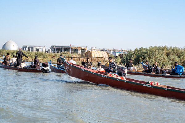 Насирия, Ирак - 20 ноября 2025 года: Группа туристов на традиционных лодках Машуф приближается к памятнику Аль-Шахиду в Чибаишских болотах