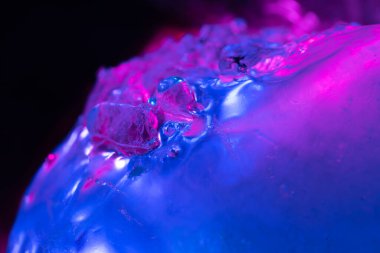 Kabarcıklı ve yansımalı renkli jel yakın plan, pembe ve mavi ışıkla aydınlatılmış.