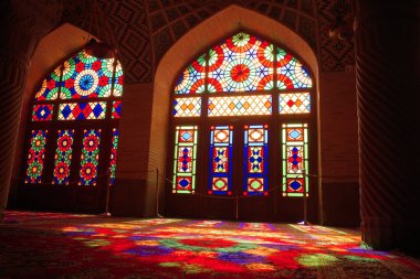 Canlı vitraylı pencereler, tarihi bir binanın zemininde renkli desenler oluşturuyor.