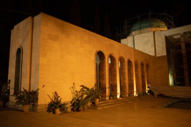 Geceleri çok güzel aydınlatılmış, kemerli pencereleri ve etrafı bitkiler ve iskelelerle çevrili bir kubbesi olan bir taş bina.