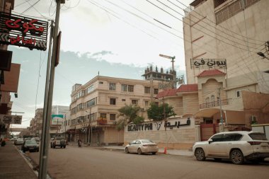 Park halindeki arabaları ve bulutlu bir gökyüzü altında klasik mimarisi olan temiz bir şehir caddesinin geniş açılı perspektifi..