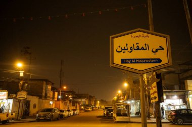 Yapay sıcak sodyum-buhar aydınlatması altında bir belediye bölge levhası içeren gece kentsel manzarası