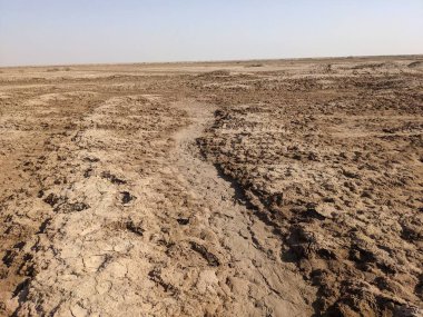 Çorak toprağı ve görünen bir yolu olan kuru ve çatlak bir arazi.