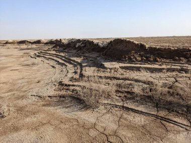 Çürümüş toprak oluşumları ve seyrek bitki örtüsüyle kuraklık ve çölleşmenin etkilerini gözler önüne seren kuru ve çatlak bir manzara..
