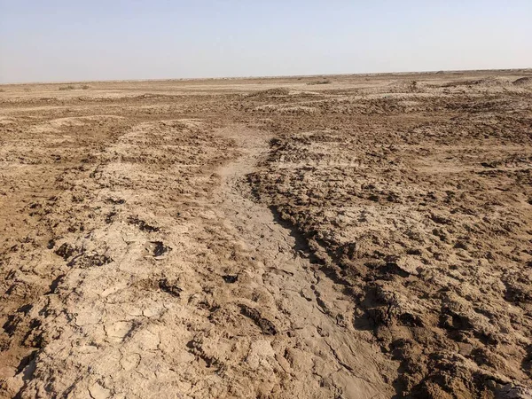 Çorak toprağı ve görünen bir yolu olan kuru ve çatlak bir arazi.