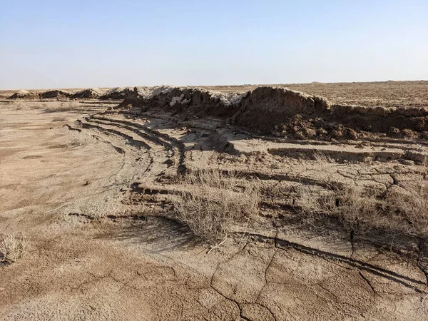 Çürümüş toprak oluşumları ve seyrek bitki örtüsüyle kuraklık ve çölleşmenin etkilerini gözler önüne seren kuru ve çatlak bir manzara..