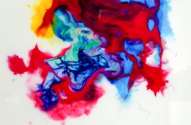 Suda dönen soyut renkli mürekkep, kırmızı, mavi, sarı ve yeşilin canlı renkleri birlikte harmanlanarak dinamik ve akışkan bir bileşim oluşturur.