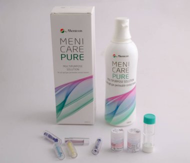 Bir şişe menicare saf çok amaçlı çözeltisi, küçük şişeler ve kaplarla çevrili, kontak lens bakımı için uygun.