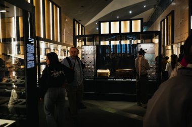 Giza, Mısır - 11 Şubat 2026: Ziyaretçiler Büyük Mısır Müzesi 'ndeki bir düşük ışık galerisinde Altın Tapınak veya Sarcophagus' a hayran kaldılar