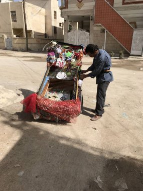 Güneşli bir sokakta süslü bir çekçek ayarlayan bir adam.