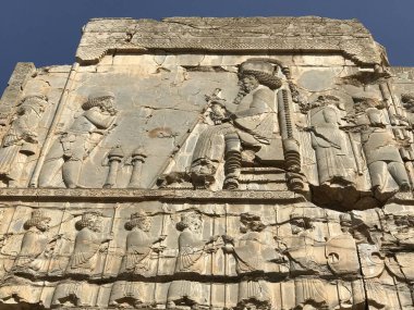 Antik taş levrek rahatlaması, açık gökyüzü altında oturan kral ve görevlilerle kraliyet alayını gösteriyor.