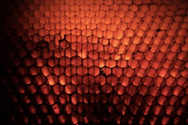 Parlayan kırmızı-turuncu bal peteği ya da sürüngen ölçekli doku soyut makrosu, koyu renkli ve ılık ışıklı ışıklandırılmış desen arkaplanı..