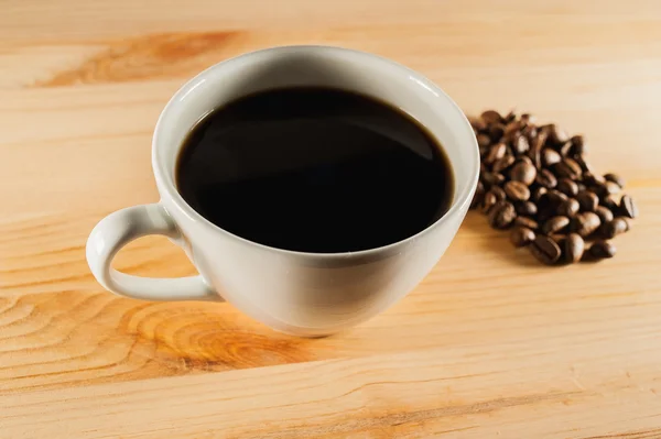 Beyaz fincan kahve ahşap arka plan ve kahve çekirdekleri