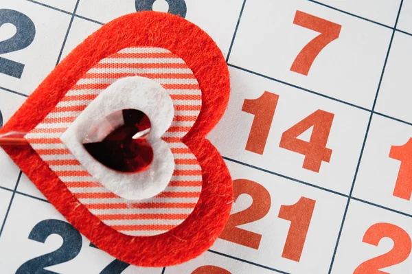 Febrero 14, 2015 en el calendario, San Valentín, el corazón de fieltro rojo . Imágenes de stock libres de derechos