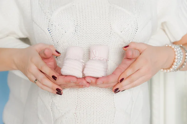 Hands on the abdomen of a pregnant woman with pink booties — Stock Photo, Image