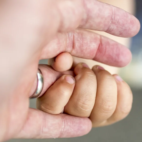 Child is holding a ringfinger of his father — Stock Photo, Image