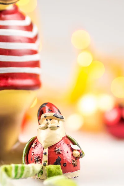 One ceramic christmas reindeer and one ceramic santa claus on white background with blurred yellow christmas lights — Stock Photo, Image