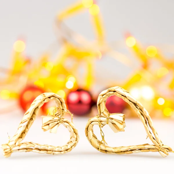 Two straw christmas hearts on white background with blurred yellow christmas lights — Stock Photo, Image