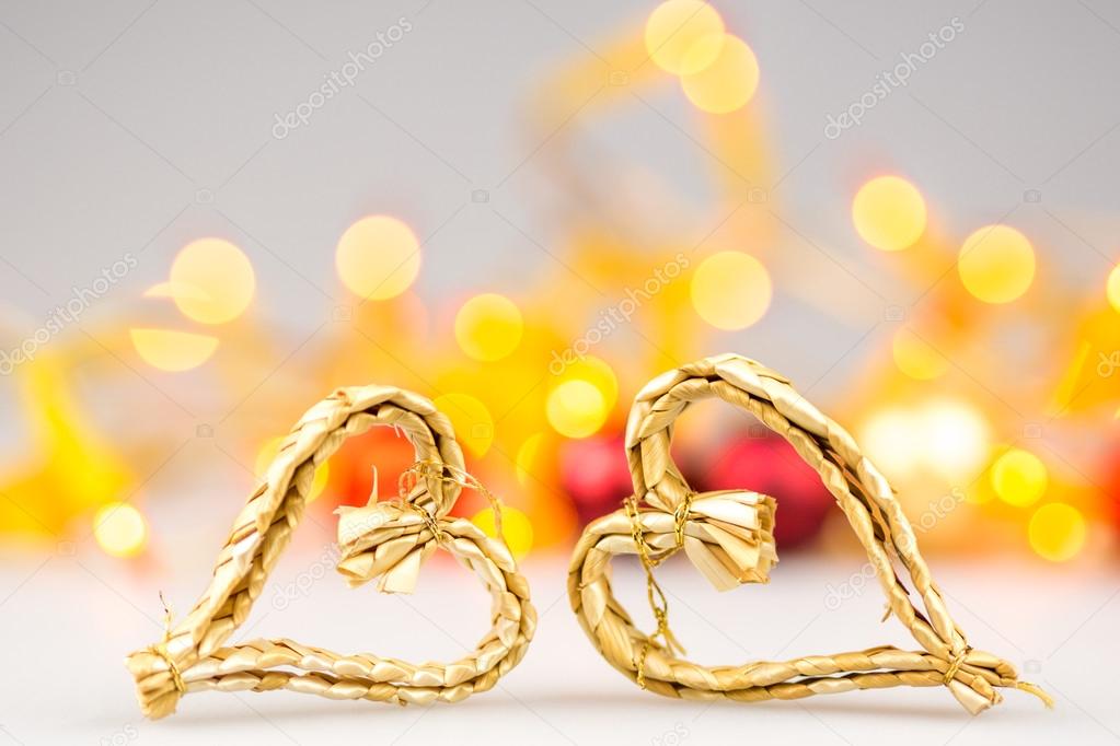 One straw christmas heart on white background with blurred yellow christmas lights