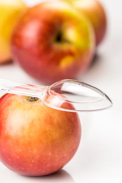 Rött äpple och genomskinliga medicin sked på bordet — Stockfoto