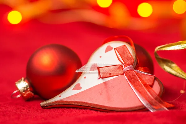 Christmas heart and balls on red background with bright yellow lights — Stock Photo, Image