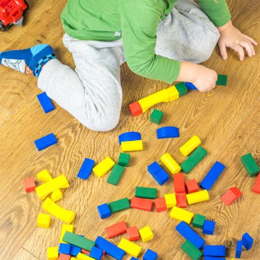 Çocuk çok renkli küpleri ile ahşap zemin üzerinde oynuyor