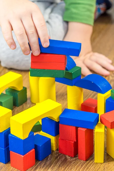 Niño está jugando con cubos multicolores en el suelo de madera —  Fotos de Stock