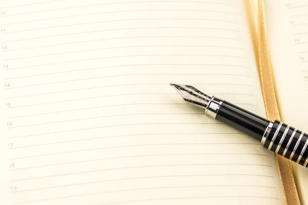 Pluma de tinta colocada en el cuaderno en blanco con líneas — Foto de Stock