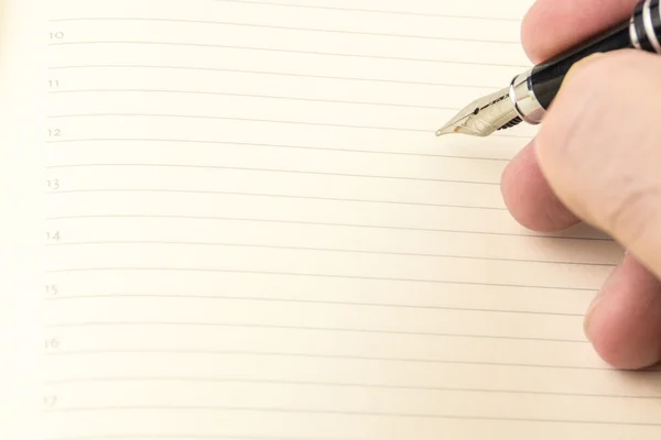 Men is writing with ink pen into the blank notebook with lines — Stock Photo, Image