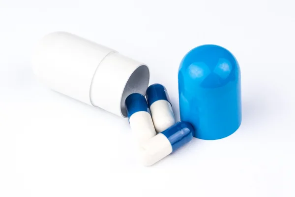 Tři malé tabletky jsou coming out z velké modré a bílé kapsle — Stock fotografie