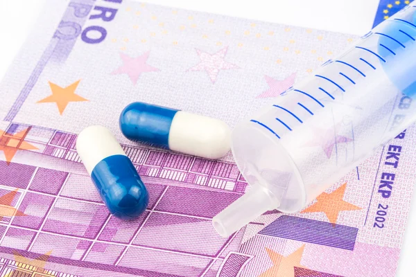 Deux petites pilules et une injection sont posées sur un billet de 500 euros — Photo