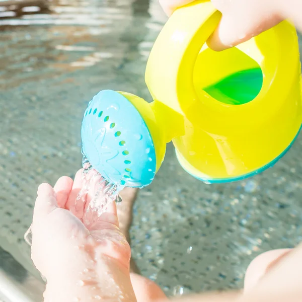 Kind spielt mit Gießkanne im Babybecken — Stockfoto