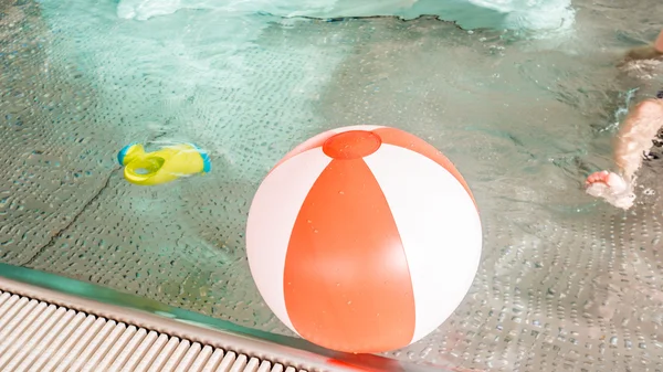 Kind, Rutsche, Gießkanne und rot-weißer aufblasbarer Ball liegen auf einer Oberfläche — Stockfoto