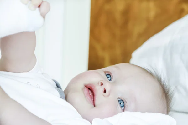 Modré oči dítě leží na posteli — Stock fotografie