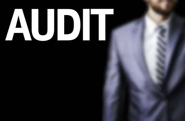 Audit written on a board with a business man on background — Stock Photo, Image