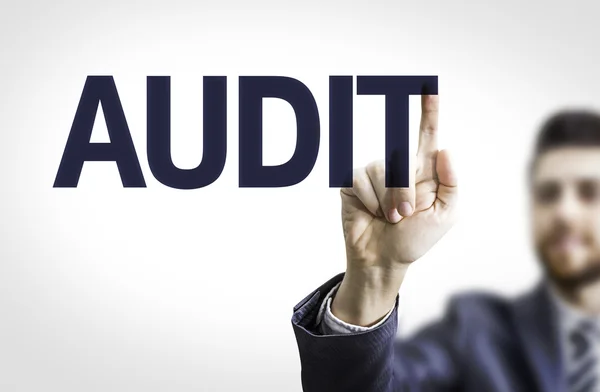 Homme d'affaires pointant vers un tableau transparent avec le texte : Audit — Photo