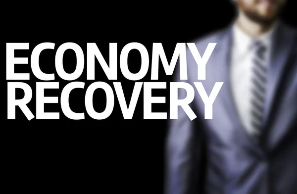 Economy Recovery written on a board with a business man — Stock Photo, Image