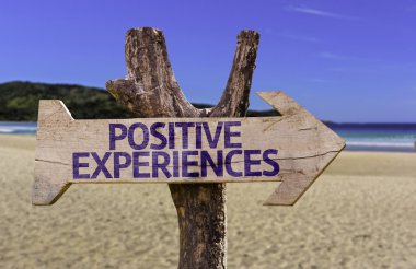 Positive Experiences wooden sign with a beach on background clipart