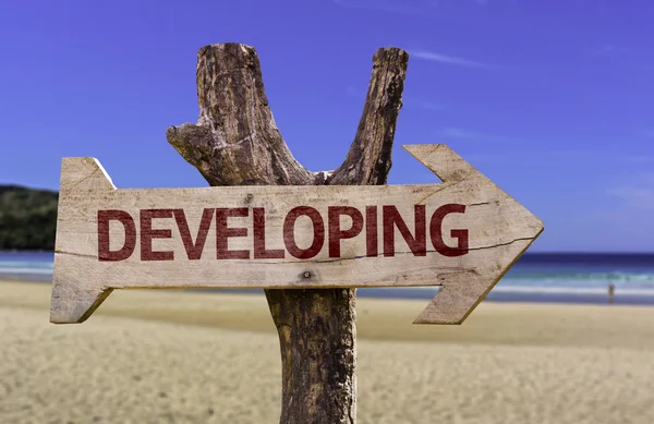 Sviluppo segno di legno con una spiaggia sullo sfondo — Foto Stock