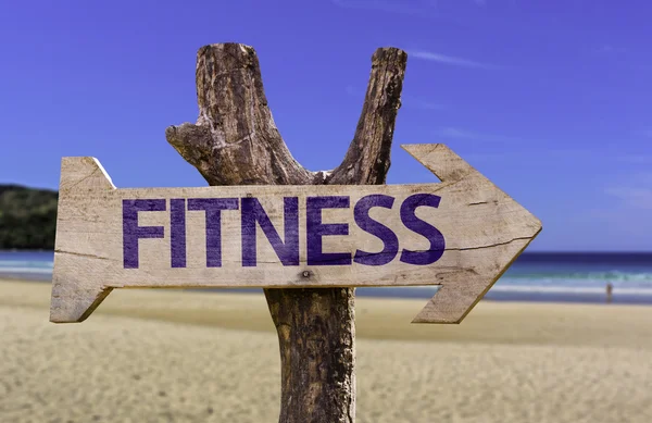 Fitness segno di legno con una spiaggia sullo sfondo — Foto Stock