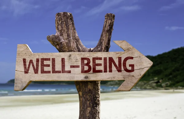 Well-Being wooden sign with a beach on background — Stock Photo, Image