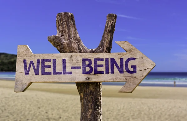 Welzijn houten bord met een strand op achtergrond — Stockfoto