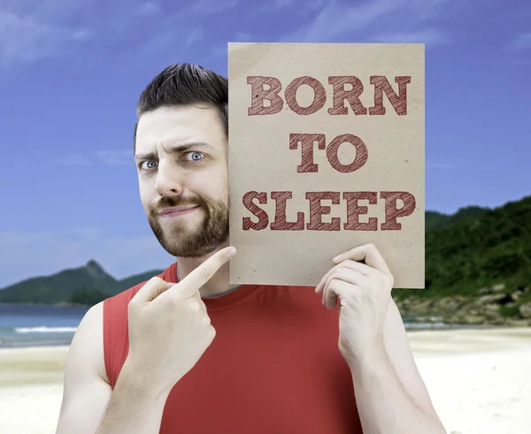 Человек с карточкой с текстом "Рождённый спать" — стоковое фото
