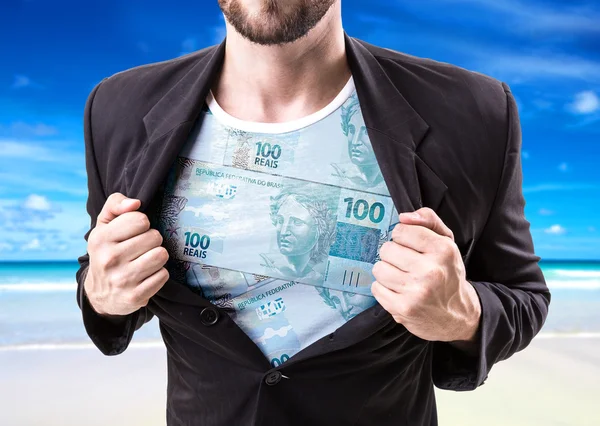 Biznesmen rozciąganie garnitur z brazylijskim pieniądze — Zdjęcie stockowe