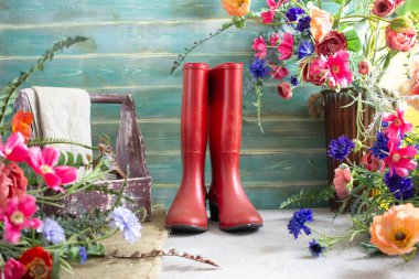 Bahçe kauçuk botlarında bahar işleri. Teneke ve çiçekleri suluyor.