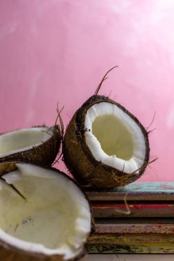 Pembe arka planda duran hindistan cevizi yarıları